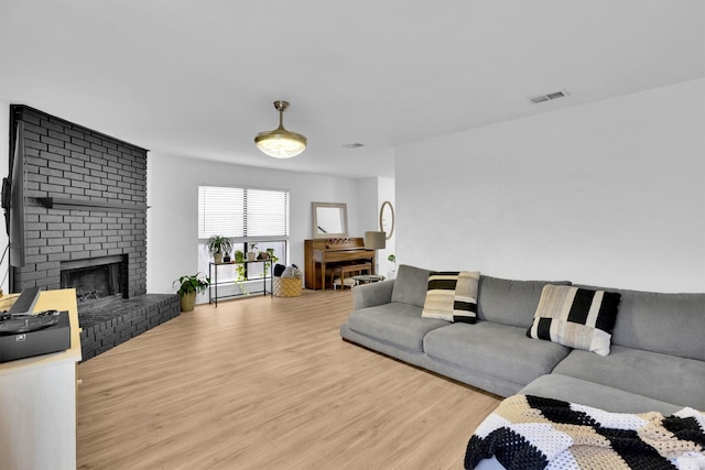 living room with a brick fireplace and light hardwood / wood-style flooring