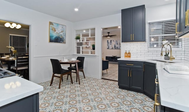 kitchen with sink, decorative backsplash, light stone countertops, and ceiling fan