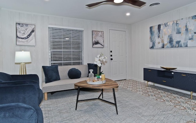 living room featuring ceiling fan and wooden walls