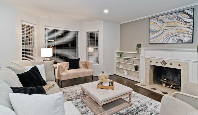 living room with a tiled fireplace, crown molding, and dark wood-type flooring