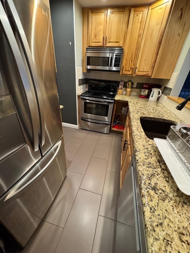 kitchen with light tile patterned floors, stainless steel appliances, and light stone countertops