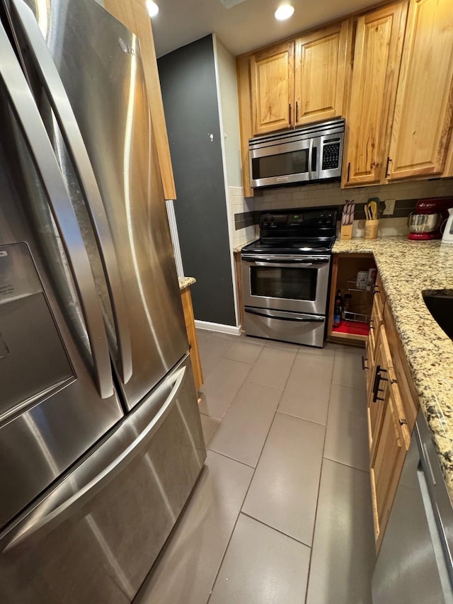 kitchen featuring light tile patterned floors, light stone countertops, and appliances with stainless steel finishes