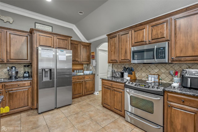 kitchen featuring appliances with stainless steel finishes, dark stone counters, tasteful backsplash, vaulted ceiling, and light tile patterned floors