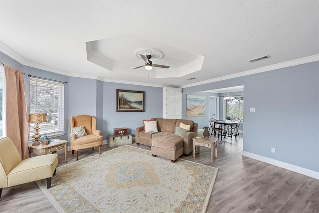 living room with a tray ceiling, ornamental molding, and light hardwood / wood-style flooring