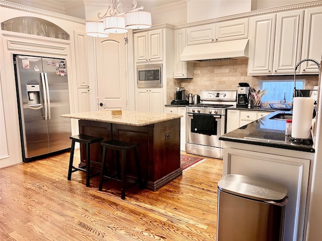 kitchen featuring extractor fan, dark stone countertops, a center island, decorative backsplash, and appliances with stainless steel finishes