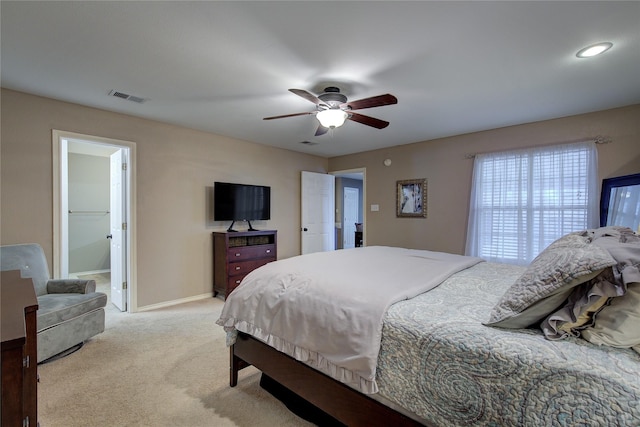 bedroom with light carpet, ceiling fan, and connected bathroom