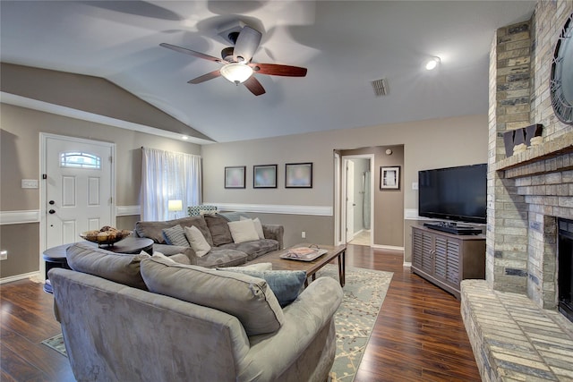 living room with ceiling fan, dark wood-type flooring, vaulted ceiling, and a fireplace