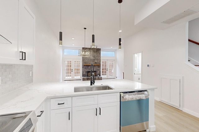 kitchen featuring tasteful backsplash, french doors, stainless steel dishwasher, white cabinets, and sink