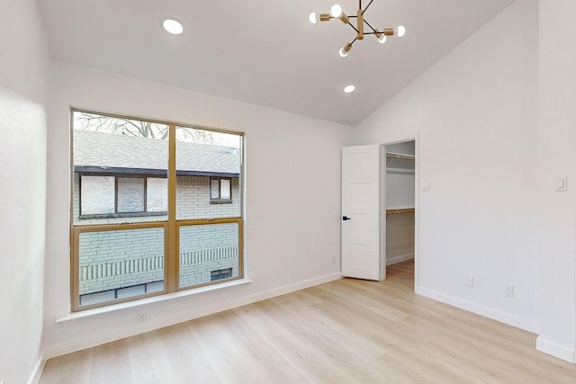 unfurnished room featuring light wood-type flooring, a notable chandelier, and vaulted ceiling