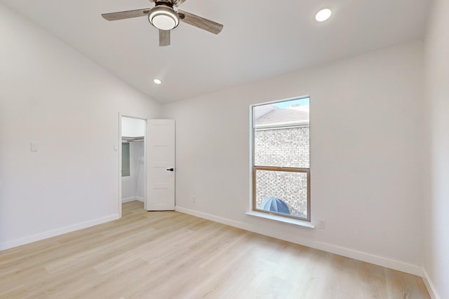 unfurnished bedroom with ceiling fan, light wood-type flooring, a closet, vaulted ceiling, and a walk in closet