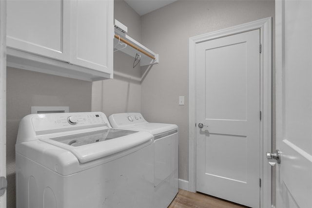 laundry room with cabinets, washer and clothes dryer, and light hardwood / wood-style floors