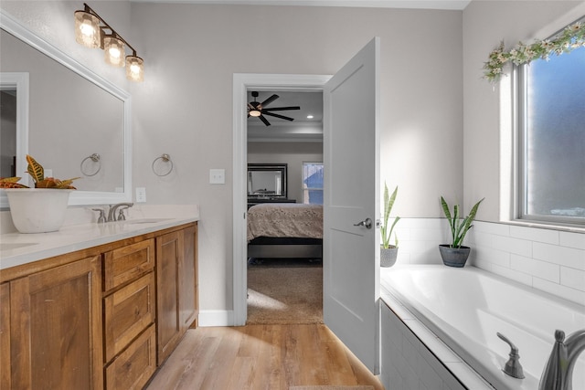 bathroom featuring ceiling fan, vanity, tiled bath, and hardwood / wood-style floors