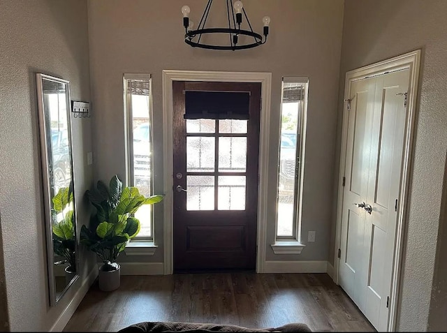 entryway with dark wood-type flooring and an inviting chandelier