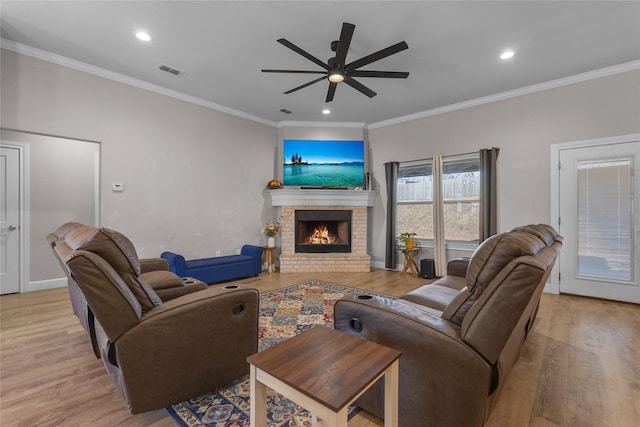 living room featuring a fireplace, light hardwood / wood-style flooring, ornamental molding, and ceiling fan