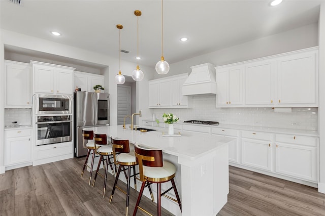 kitchen featuring white cabinets, pendant lighting, appliances with stainless steel finishes, and custom range hood