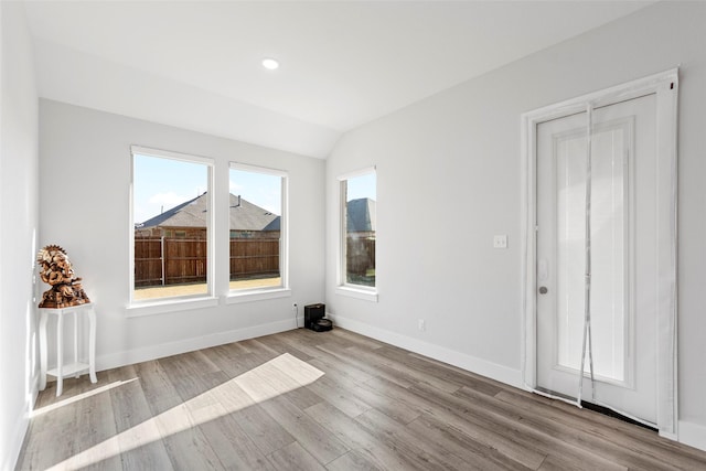 spare room featuring light wood-type flooring and vaulted ceiling