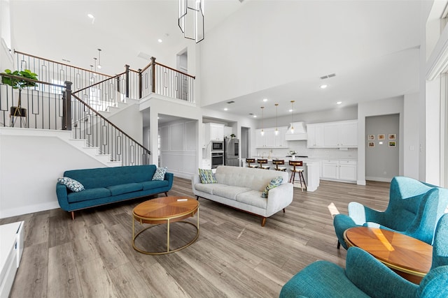 living room with a towering ceiling and light hardwood / wood-style floors