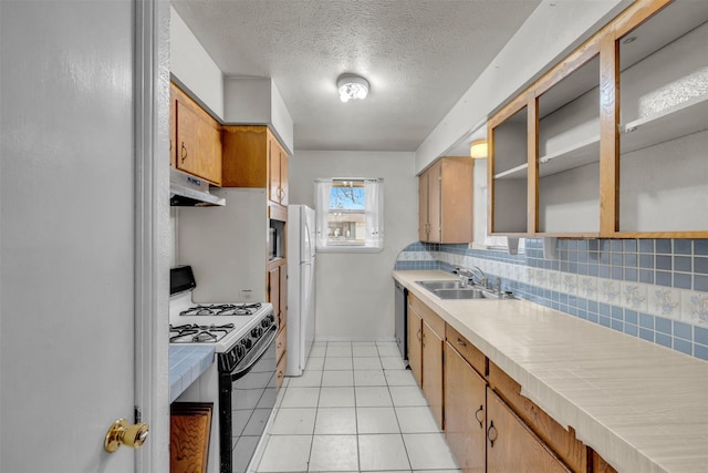 kitchen with tasteful backsplash, sink, white appliances, light tile patterned flooring, and a textured ceiling