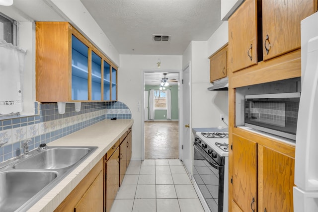 kitchen featuring light tile patterned floors, ceiling fan, white appliances, a textured ceiling, and sink