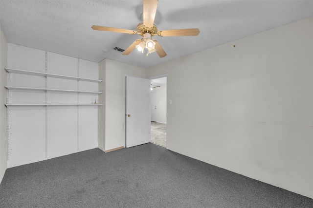 unfurnished bedroom with ceiling fan, a closet, a textured ceiling, and dark colored carpet