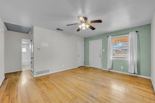 spare room featuring light wood-type flooring, ceiling fan, and a textured ceiling