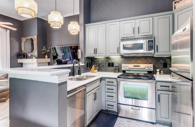 kitchen with kitchen peninsula, appliances with stainless steel finishes, tasteful backsplash, pendant lighting, and sink