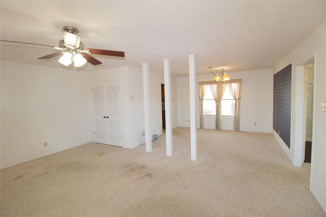 spare room featuring ceiling fan with notable chandelier and light colored carpet