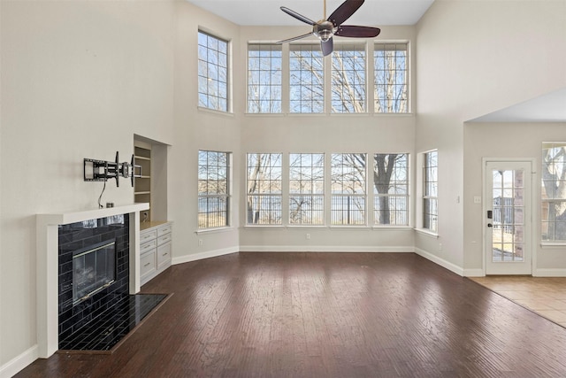 unfurnished living room with dark hardwood / wood-style flooring, a fireplace, and ceiling fan