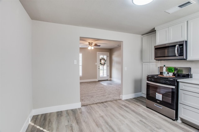 kitchen featuring white cabinetry, stainless steel appliances, ceiling fan, and light wood-type flooring