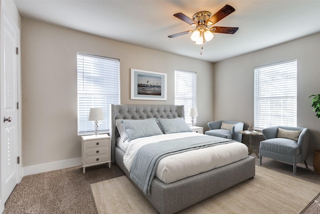 bedroom featuring multiple windows, light colored carpet, and ceiling fan