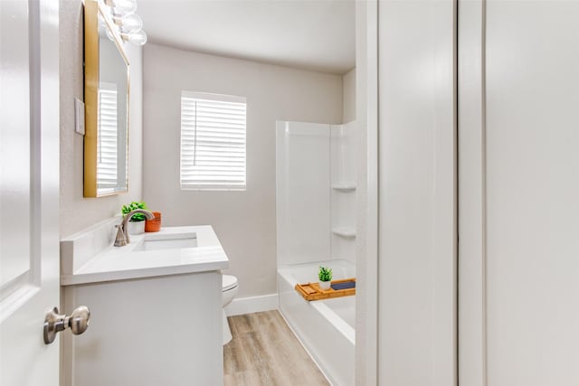 full bathroom featuring toilet, vanity, wood-type flooring, and washtub / shower combination