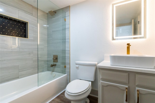 full bathroom with toilet, tiled shower / bath, hardwood / wood-style flooring, and vanity