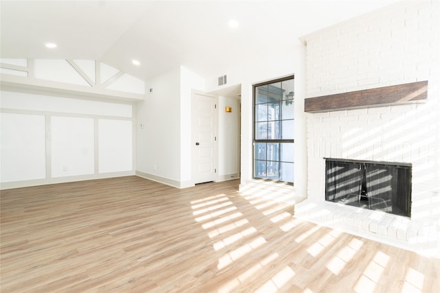 unfurnished living room featuring lofted ceiling, a brick fireplace, and light hardwood / wood-style flooring