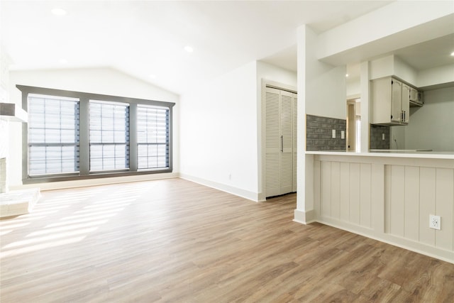 unfurnished living room featuring light wood-type flooring and lofted ceiling