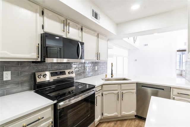 kitchen featuring decorative backsplash, appliances with stainless steel finishes, sink, and light hardwood / wood-style flooring