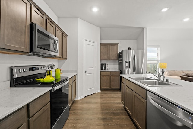 kitchen with light stone countertops, appliances with stainless steel finishes, sink, and dark hardwood / wood-style flooring