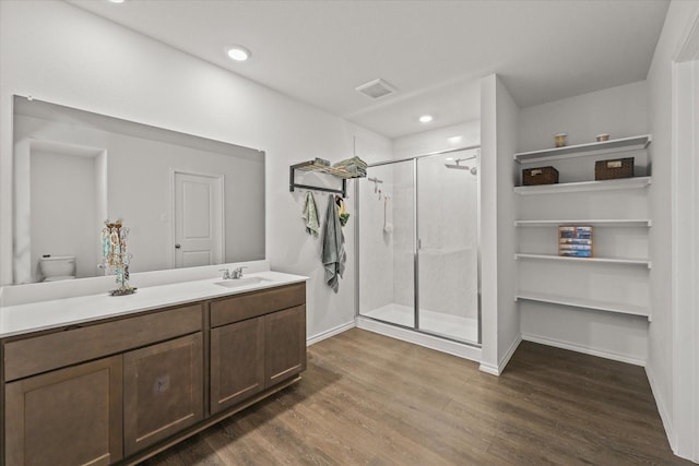 bathroom featuring toilet, vanity, a shower with shower door, and hardwood / wood-style floors