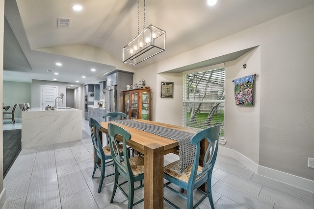 dining room with vaulted ceiling, a notable chandelier, and sink