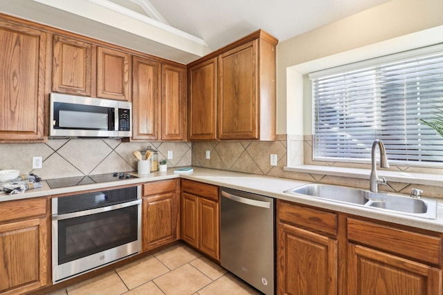 kitchen featuring lofted ceiling, decorative backsplash, sink, appliances with stainless steel finishes, and light tile patterned floors