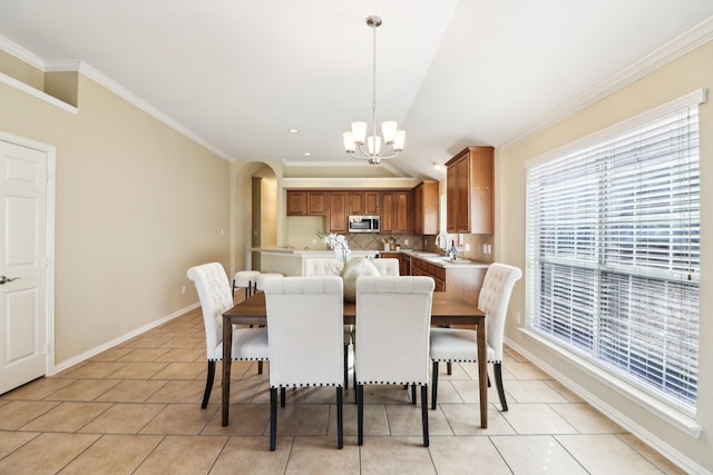 tiled dining area with sink, crown molding, lofted ceiling, and a chandelier