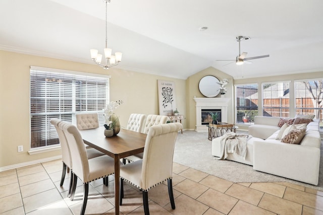 dining room with ceiling fan with notable chandelier, light tile patterned flooring, and vaulted ceiling