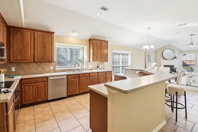 kitchen featuring lofted ceiling, sink, hanging light fixtures, a kitchen breakfast bar, and stainless steel appliances