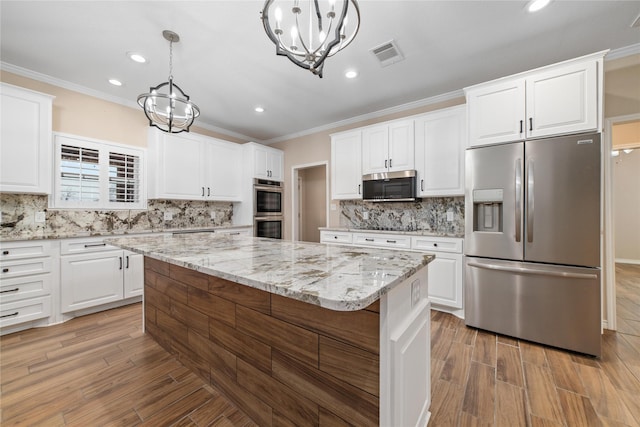 kitchen featuring decorative light fixtures, white cabinetry, appliances with stainless steel finishes, and a kitchen island