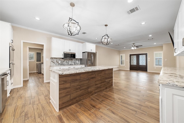 kitchen with stainless steel appliances, pendant lighting, white cabinets, light stone counters, and a center island