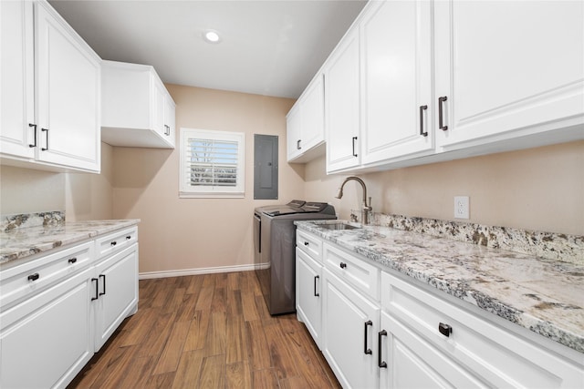 laundry area featuring cabinets, washing machine and clothes dryer, sink, dark hardwood / wood-style floors, and electric panel