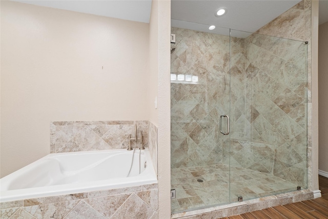 bathroom featuring wood-type flooring and shower with separate bathtub