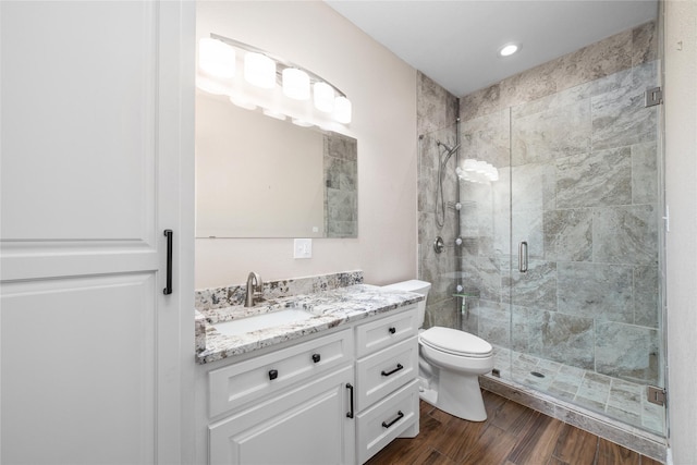 bathroom with toilet, vanity, a shower with door, and hardwood / wood-style flooring