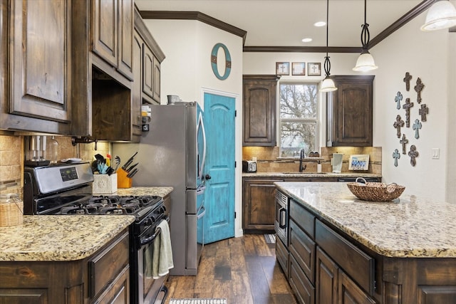 kitchen featuring dark brown cabinetry, decorative light fixtures, stainless steel appliances, sink, and backsplash