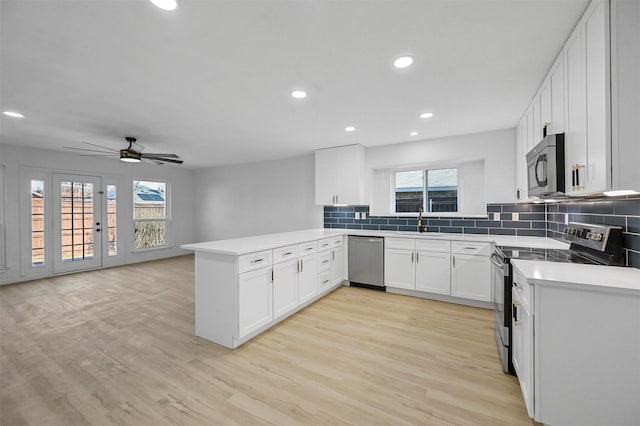 kitchen featuring kitchen peninsula, appliances with stainless steel finishes, light wood-type flooring, tasteful backsplash, and white cabinetry