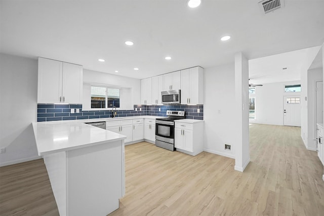 kitchen with white cabinets, appliances with stainless steel finishes, and kitchen peninsula